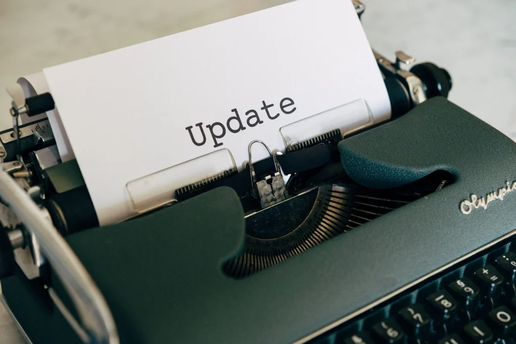 A typewriter with a sheet of paper displaying the word "Update" typed in large, clear letters. The image focuses on the typewriter and the paper.