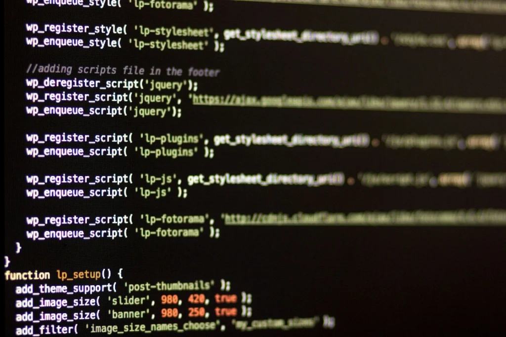 Nahaufnahme eines Computerbildschirms mit Zeilen von WordPress-bezogenem PHP-Code, einschließlich Funktionen zum Registrieren von Stylesheets und Skripten sowie zum Einstellen von Bildgrößen. Der Hintergrund ist dunkel und der Text ist durch Syntax hervorgehoben.